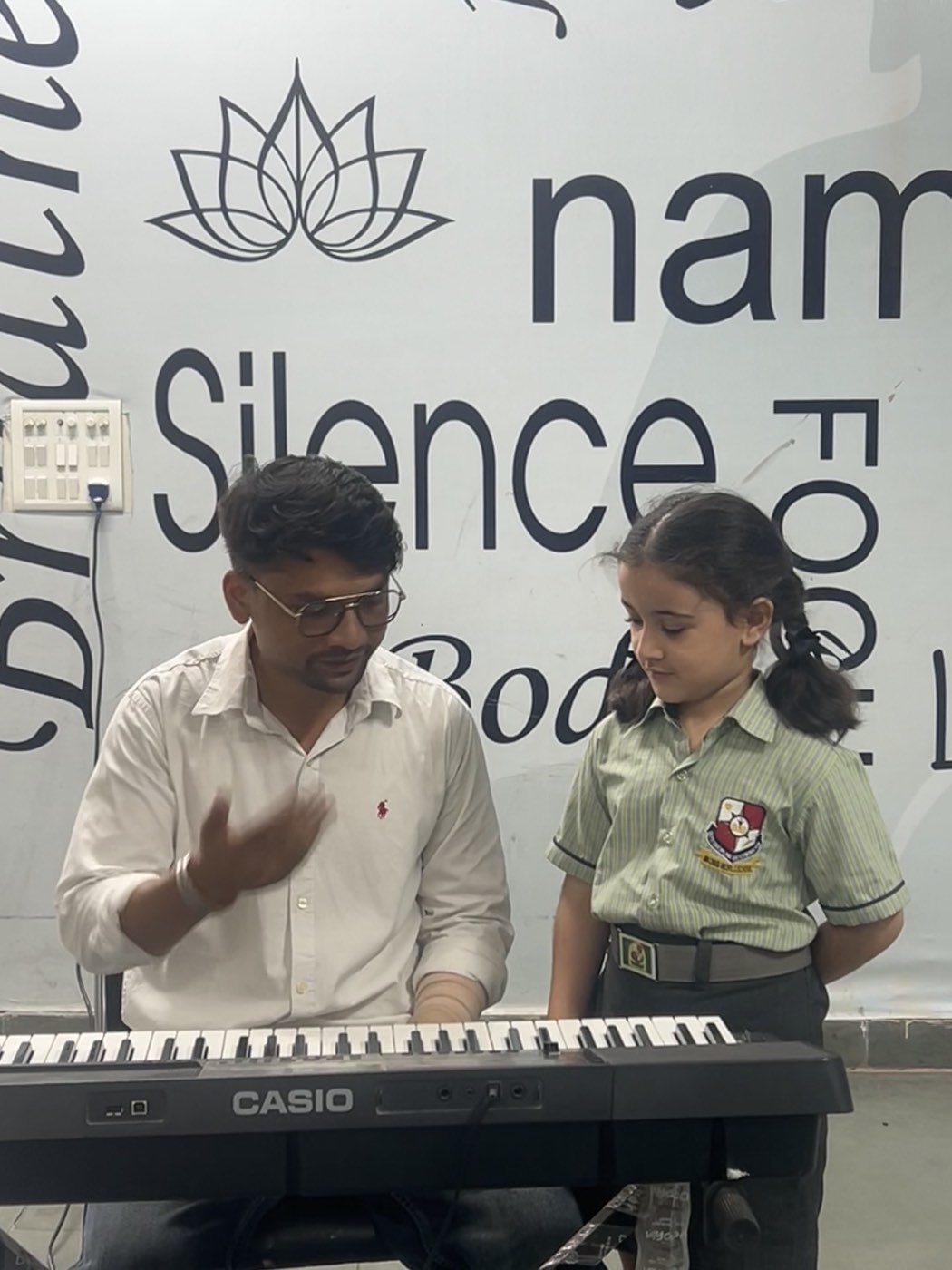 A teacher guiding a student at the keyboard in the Music Lab