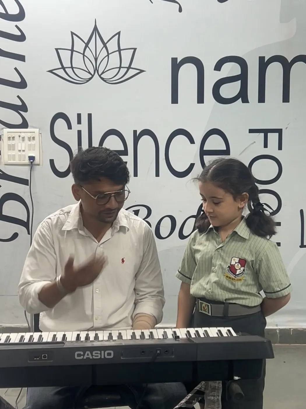 A teacher guiding a student at the keyboard in the Music Lab